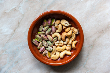 A mixed bowl of unshelled pistachios and cashews centered composition