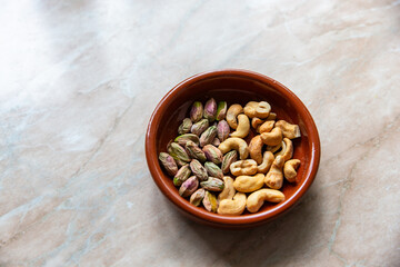 Bowl of unshelled pistachios and salted cashews
