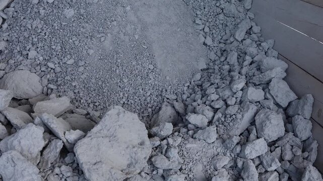 Dry crushed limestone rubble and fine gravel fill a wooden container forming a textured industrial pile used for construction renovation or landscaping applications