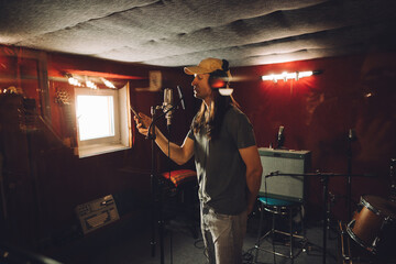 Singer recording song using smartphone in professional studio