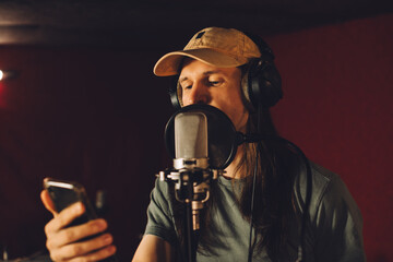 Singer recording song using smartphone app in professional studio