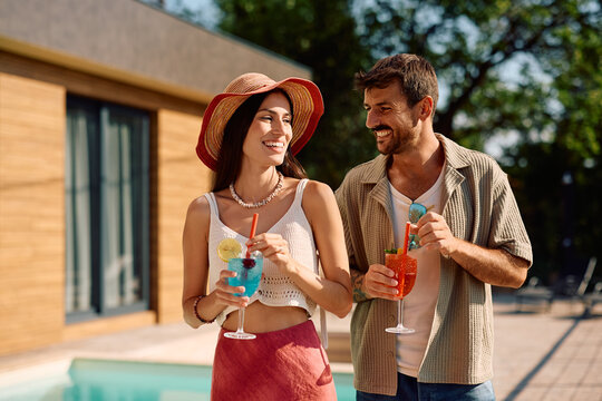 Happy couple drinking cocktails at poolside in summer. - Powered by Adobe