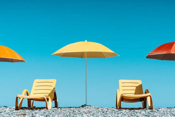 Colorful Beach Umbrellas and Sun Loungers on a Pebble Seaside