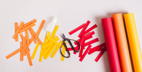 Strips of colored paper, scissors and glue to make paper garlands top view web banner
