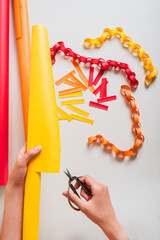 Female hands cutting a roll of paper into strips to make a paper chain