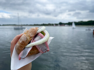 Traditional north german street food snack wheat bun with marinated herring matjes fish with onion...