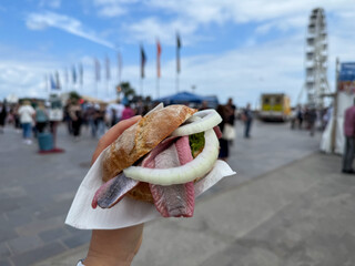 Traditional north german street food snack wheat bun with marinated herring matjes fish with onion...