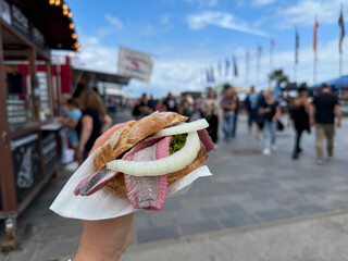 Traditional north german street food snack wheat bun with marinated herring matjes fish with onion...