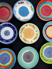 Colorful Ceramic Hand-Painted Grater Plates on a Black Background Top View