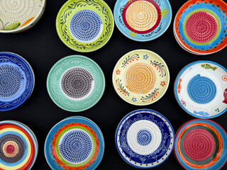 Colorful Ceramic Hand-Painted Grater Plates on a Black Background Top View