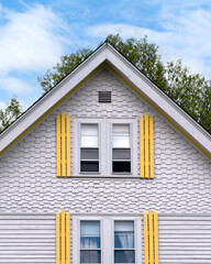 Charming gable-end view of a white house with yellow shutters in Brighton, Massachusetts, USA