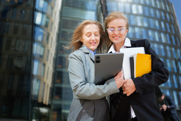 Two professionals share ideas outdoors at a modern office building in bright daylight