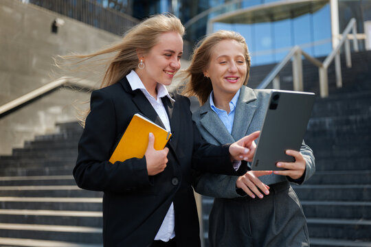Two colleagues enthusiastically discussing ideas while reviewing a tablet outdoors