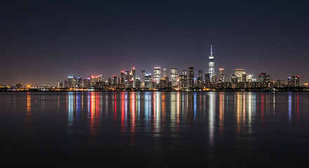 Fototapeta premium Nighttime City Skyline with Illuminated Buildings and Reflections on Tranquil Water