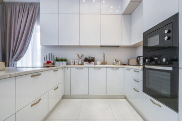 Elegant kitchen design with white furniture and modern appliances. Stylish accessories 
complement...