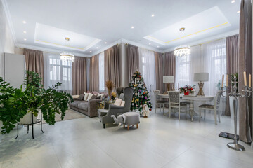 An elegant living room decorated with a Christmas tree, stylish furniture and warm lighting in a...