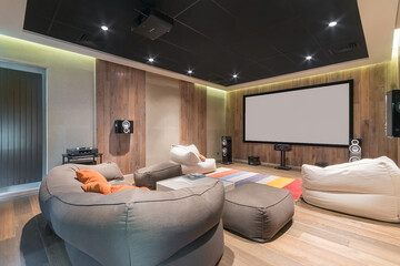 A cozy home cinema with comfortable upholstered chairs, a large screen and a modern sound system in...