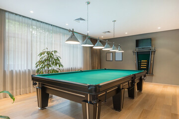 An elegant billiard room with a green table and modern decor in a well-lit room.
