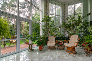 A delightful indoor garden with lounge chairs, green plants and a wonderful view of the 
summer...