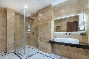 A simple bathroom design with a glass shower, a stylish sink on a black countertop and a backlit...