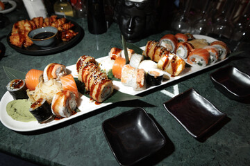 Delicious assortment of sushi featuring various rolls with sushi rice, fish, and toppings. The elegant platter is complemented by soy sauce, ginger, and wasabi, ready for serving.