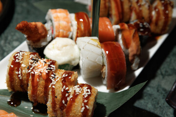 Delicious assortment of sushi featuring various rolls with sushi rice, fish, and toppings. The elegant platter is complemented by soy sauce, ginger, and wasabi, ready for serving.