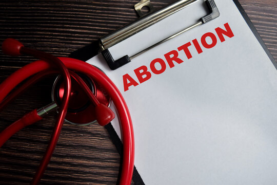 Concept of ABORTION write on clipboard isolated on Wooden Table.