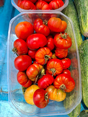Fresh Raf tomatoes in a plastic container at a farmers market in Spain during a sunny afternoon