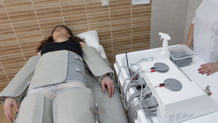 Relaxing pressotherapy session, young woman in clinic for body detox and beauty