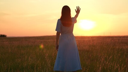 Obraz premium Happy girl in park stretching her hand to sun. Prayer god nature solitude. Happy girl stretching her hand to sunset. Sunlight through fingers of young woman. Travel in nature. Freedom rest in outdoors