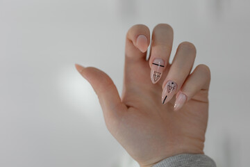 The girl shows her hands with an elegant manicure, close-up. Beige gel nail polish, elegant almond-shaped long nails, light colors, glamour