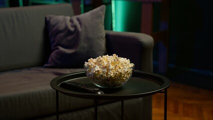 Contemporary living space with remote control and snacks on table reflecting preparation for movie...