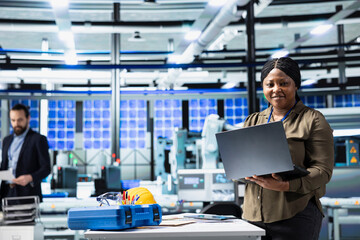 African american female consultant walks through manufacturing plant, inspecting solar panel...