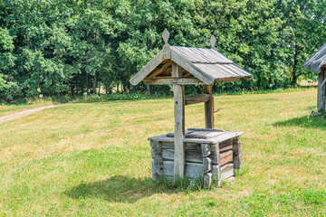 Rustic Japanese teahouse in a lush, Central European park setting Simple wooden structure with tiled roof and green surroundings Daytime scene with ample sunlight casting shadows
