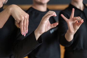 A man and two women demonstrate a phrase in sign language. 