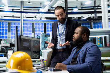 Two general directors business associates oversee production process and data on pc in solar...