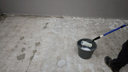 Skilled construction worker waterproofing concrete surface, applying protective sealant with roller and primer for preventing water damage and ensuring surface integrity