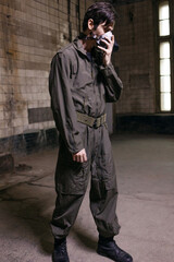 A young man in a military jumpsuit with a protective breathing mask, portrait in a grunge environment