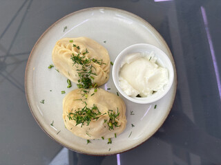 Traditional uzbek dumplings, manti with sour cream and herbs in asian restaurant