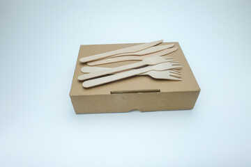 A biodegradable wooden cutlery forks and knives placed on a brown kraft paper food box. Perfect for sustainable packaging, zero waste, or eco friendly, restaurant, catering