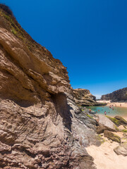 Stunning view of Porto Covinho beach with golden cliffs, calm turquoise waters, and clear blue sky on a sunny day in Portugal’s scenic Alentejo coast.