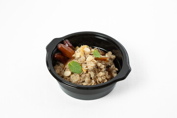 Oatmeal with dates and nuts on a plate over white background