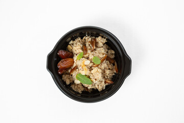 Oatmeal with dates and nuts on a plate over white background