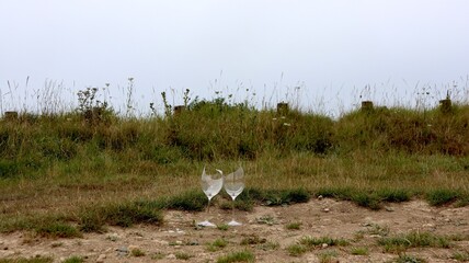 Wild party night – two broken champagne glasses Wine glasses in front of the dunes on the beach in Normandy, France.