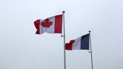 The flags of Canada and France fly over the beaches of Normandy.