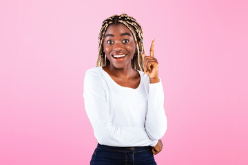 Eureka. Inspired young African American woman raising finger up and smiling at camera, posing on...