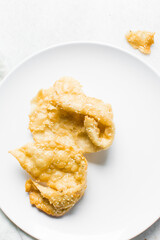 Overhead view of dublan northern nigerian snack, top view of dublan on a white plate, flaky fried dough coated in syrup and sesame