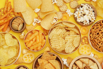 Colorful mix of salty snacks for beer varieties: chips and pretzels, onion rings and crackers. Non-healthy junk food background