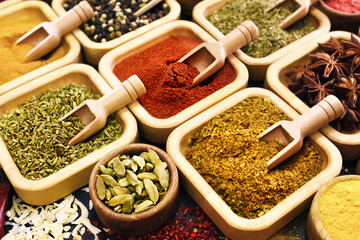 Colorful mix of herb and spice varieties: curry and coriander, turmeric and cumin, paprika and pepper, mustard and salt, cardamon and oregano and saffron. Selective focus, shallow DOF