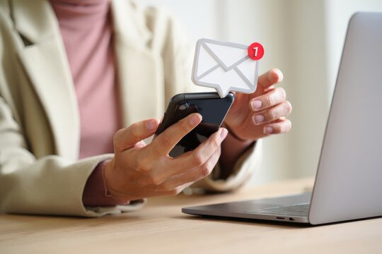 Businesswoman checking email on smartphone, noticing new email notification, engaging with mobile technology, emphasizing email marketing and communication in the modern workplace